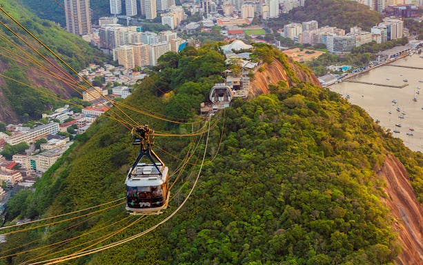 Tourists in Sugarloaf Mountain cable car viewing Rio de Janeiro cityscape.