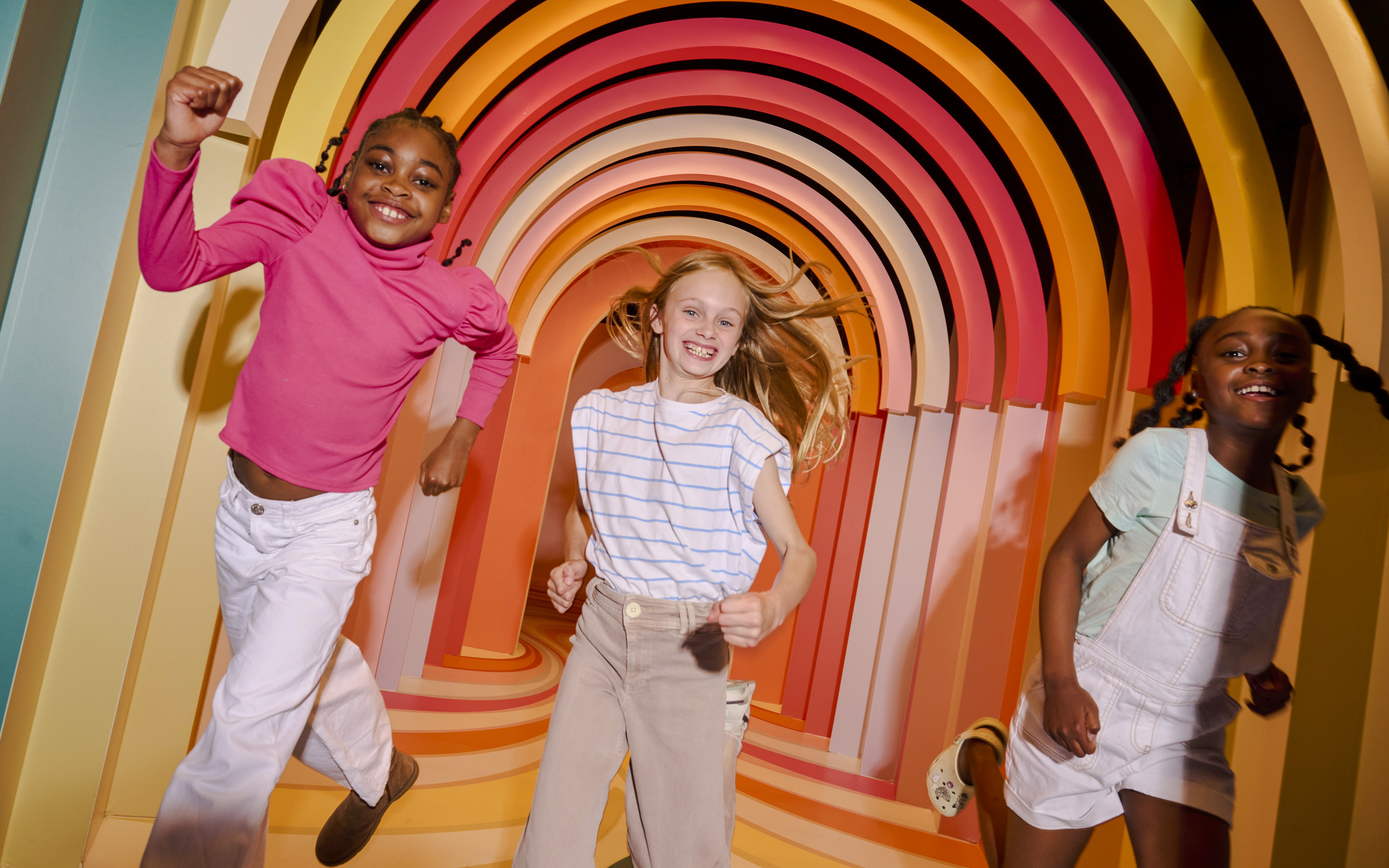 Children enjoying colorful archway at Twist Museum, London.