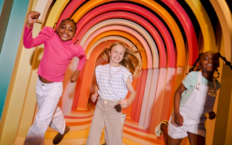 Children enjoying colorful archway at Twist Museum, London.