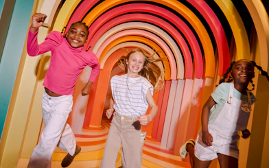 Children enjoying colorful archway at Twist Museum, London.