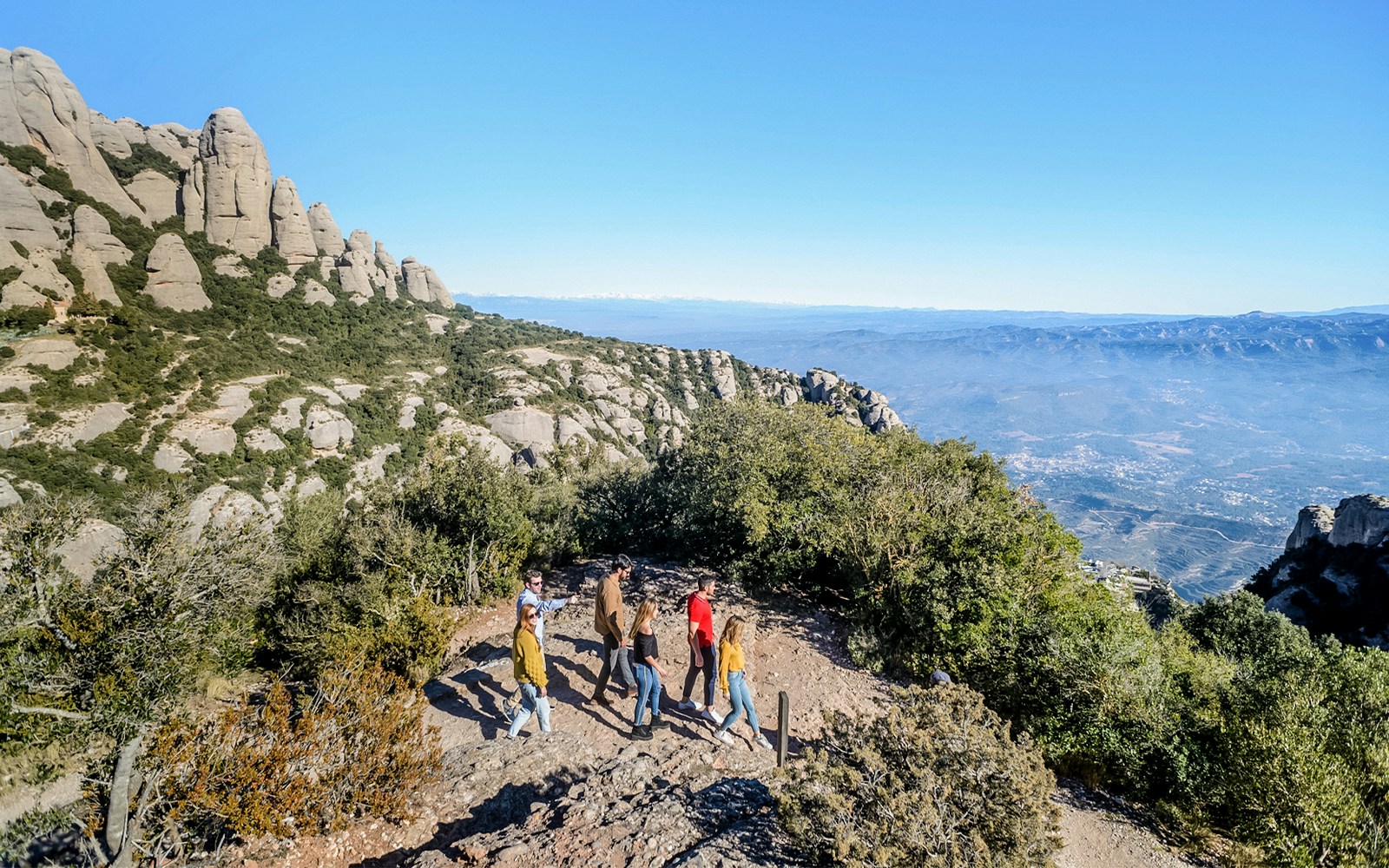 Tourists hiking with guide towards Montserrat Monastery in Spain.