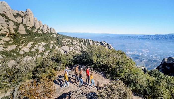 Tourists hiking with guide towards Montserrat Monastery in Spain.
