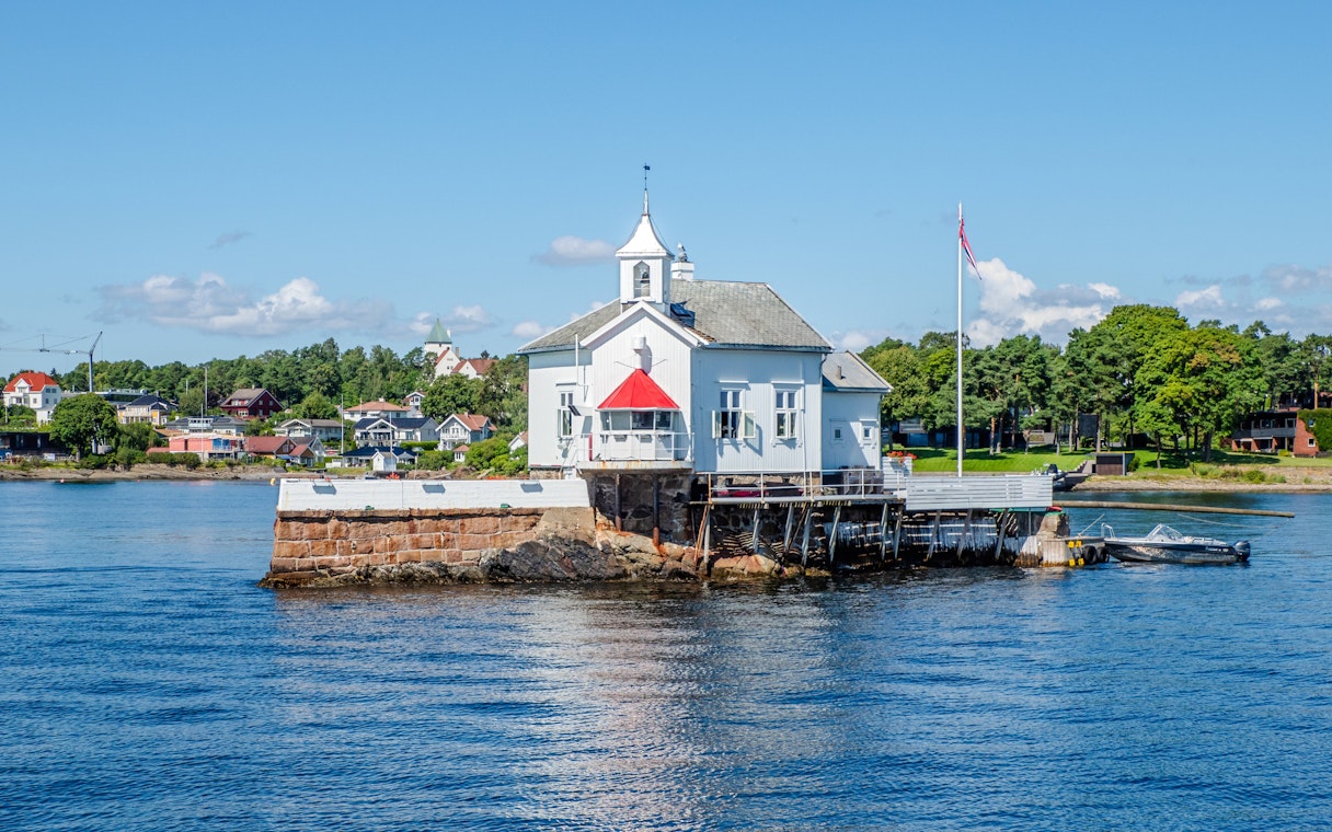 Dyna Lighthouse on a small island near Bygdøy, Norway, surrounded by water and coastal homes.