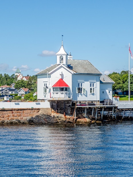Dyna Lighthouse on a small island near Bygdøy, Norway, surrounded by water and coastal homes.