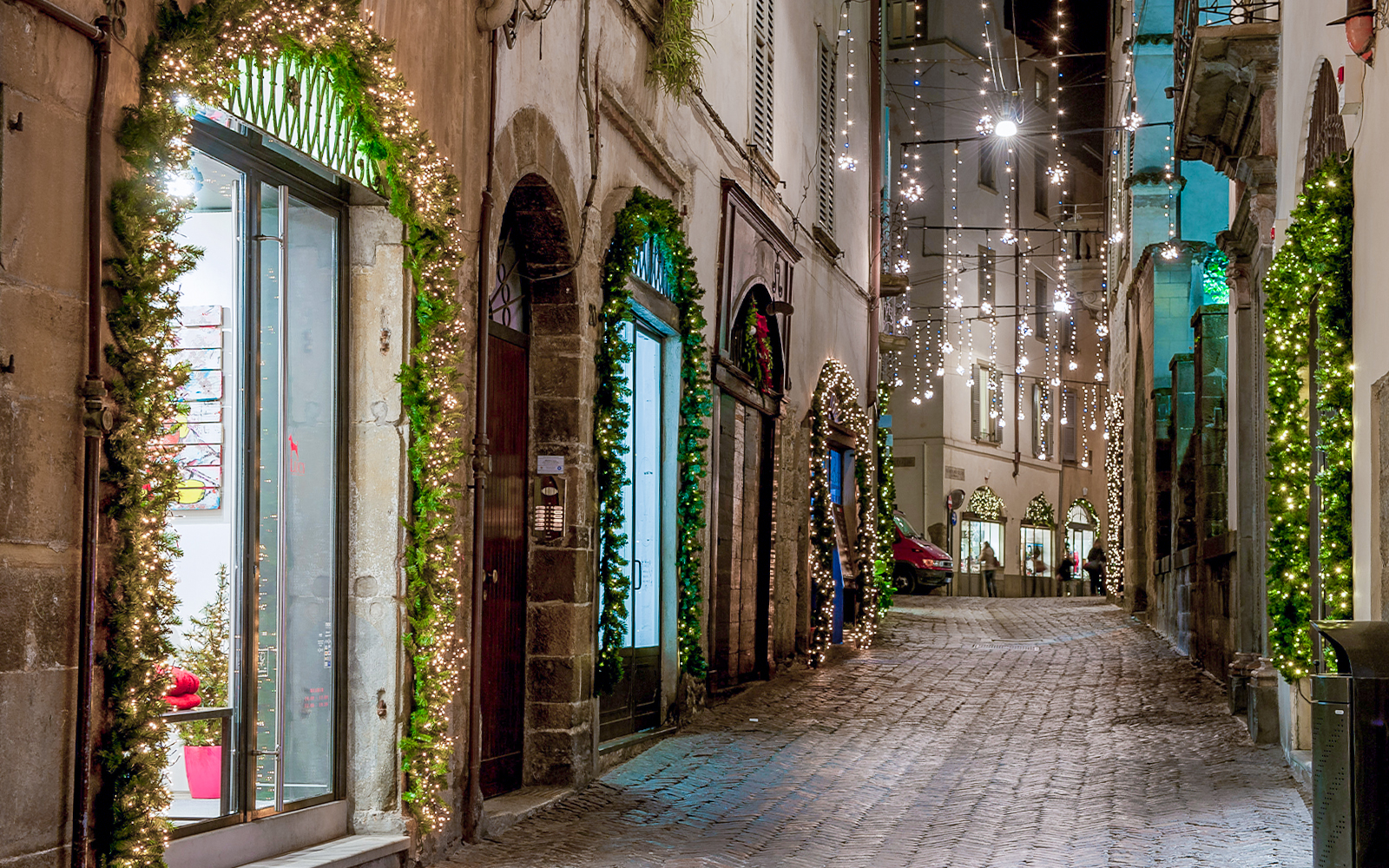 Barcelona streets at night with illuminated buildings and bustling pedestrians.