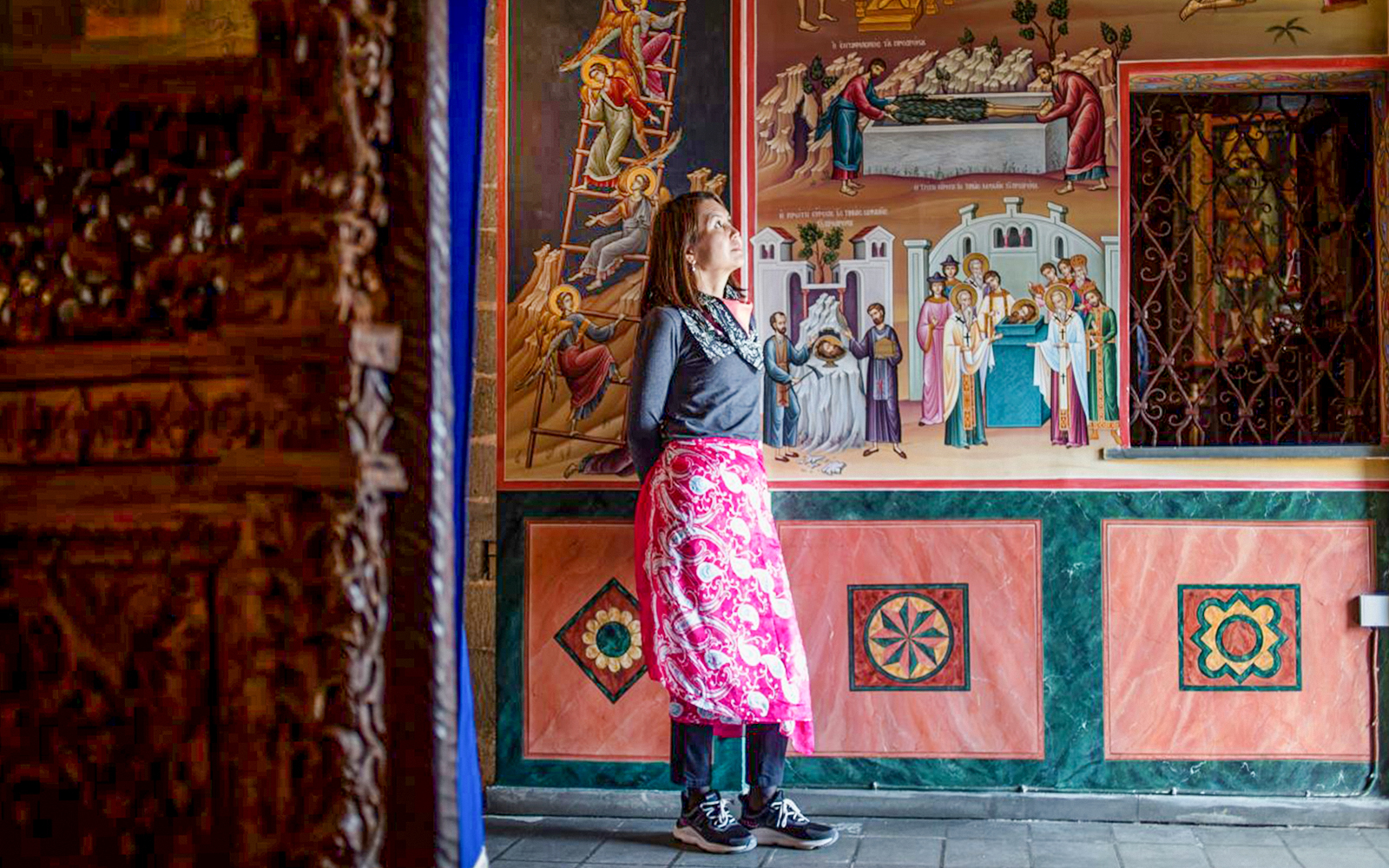 Female guest admiring frescoes inside Meteora Monastery, Greece.