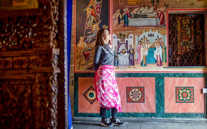 Female guest admiring frescoes inside Meteora Monastery, Greece.