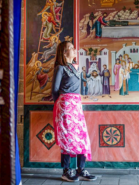 Female guest admiring frescoes inside Meteora Monastery, Greece.