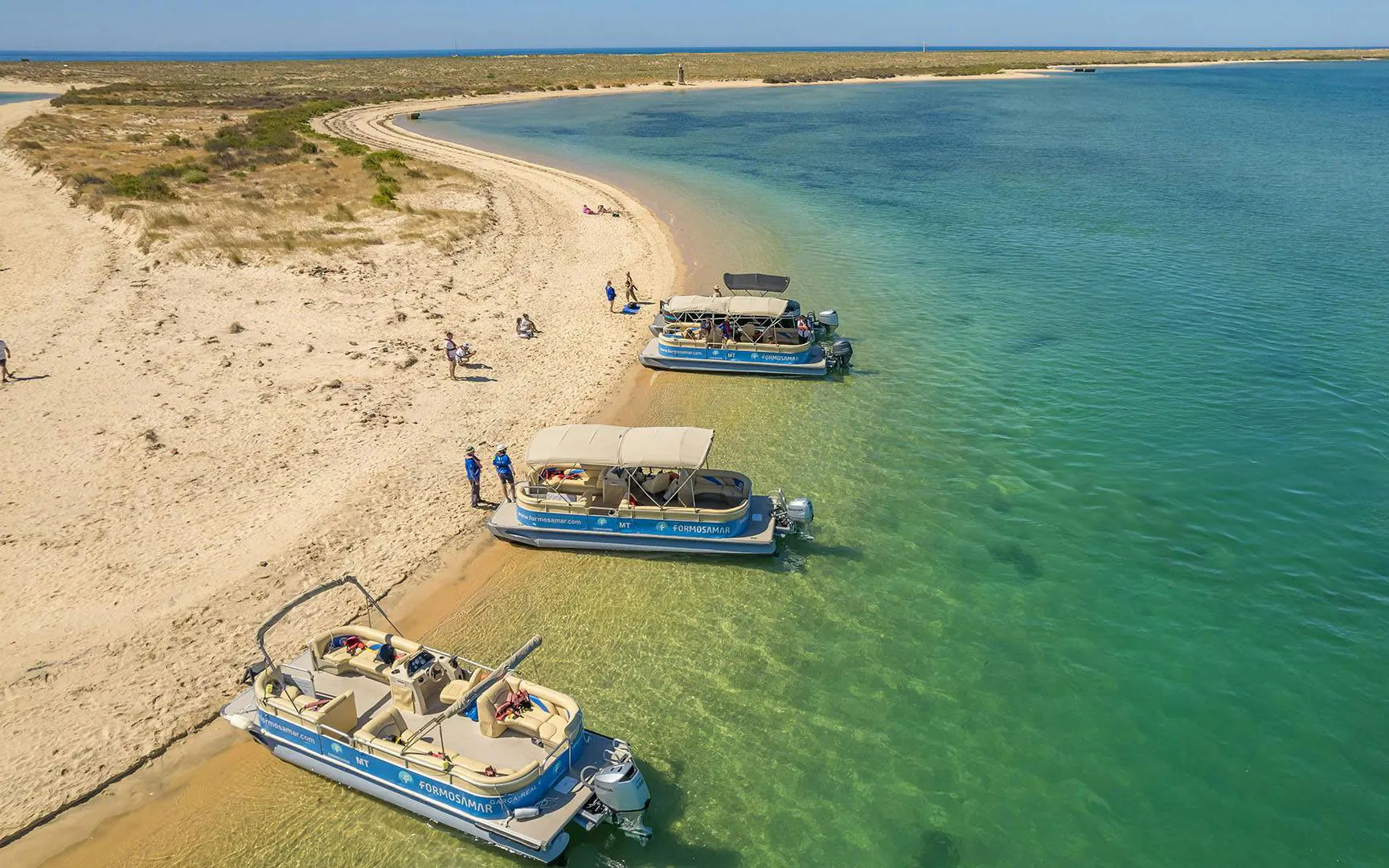 Boats docked on sandy shore of Deserta Island during Ria Formosa tour.