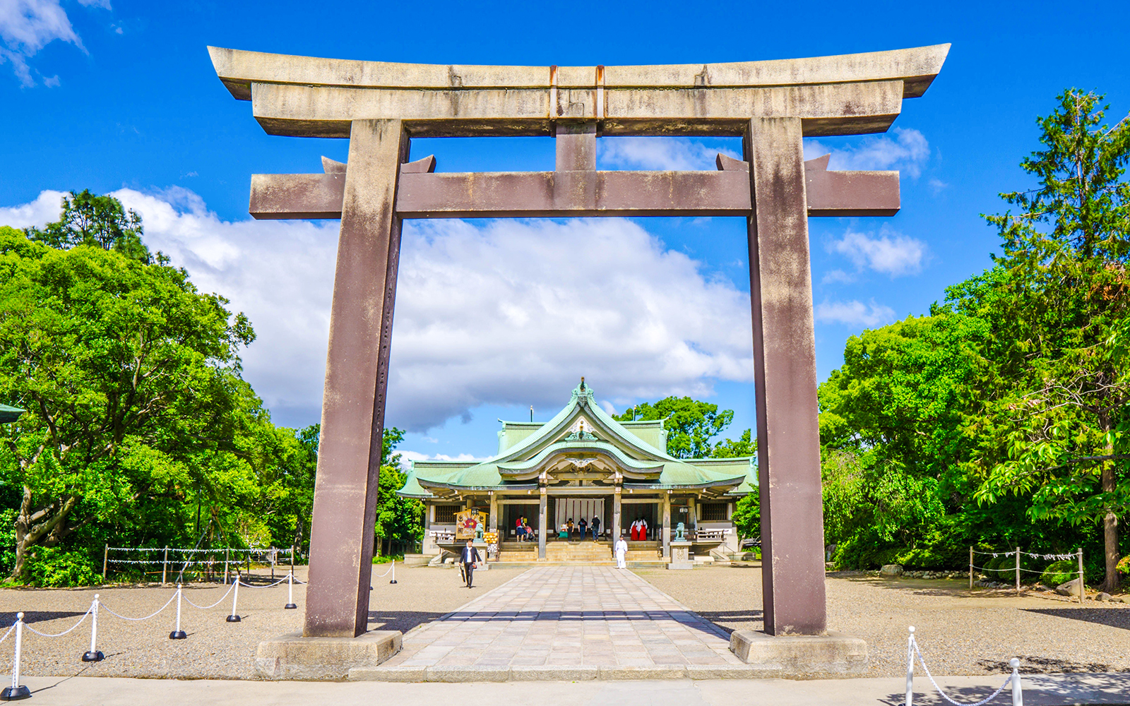 Torii gate leading to Hokoku Shrine in Osaka, surrounded by lush greenery.