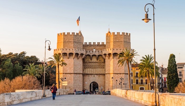 Torres de Serranos gate in Valencia with people walking on the bridge.