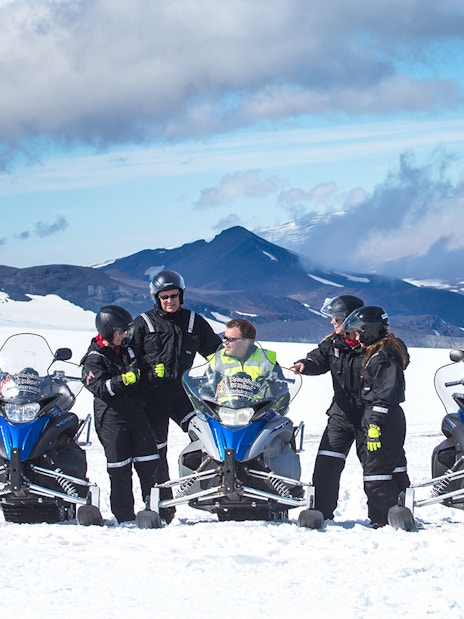 Snowmobile riders on Langjokull Glacier with snowy mountains in the background.