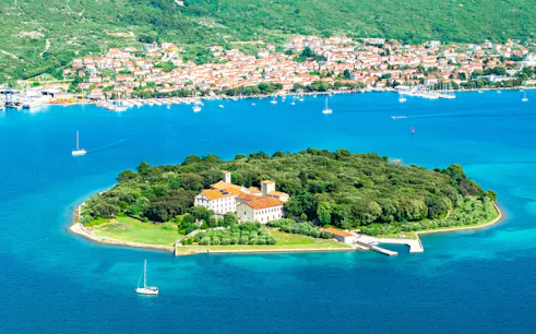 Košljun Monastery on a lush island surrounded by blue waters, Krk island, Croatia.