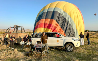 Hot air balloon preparation in Cappadocia with crew and guests, sunrise tour setup.