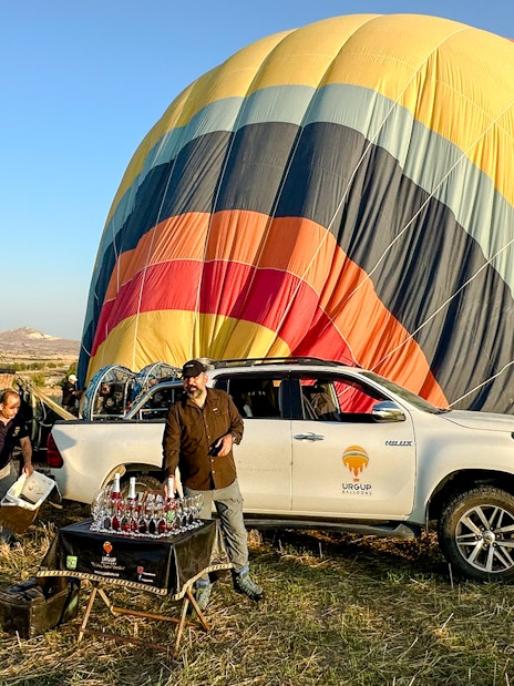 Hot air balloon preparation in Cappadocia with crew and guests, sunrise tour setup.