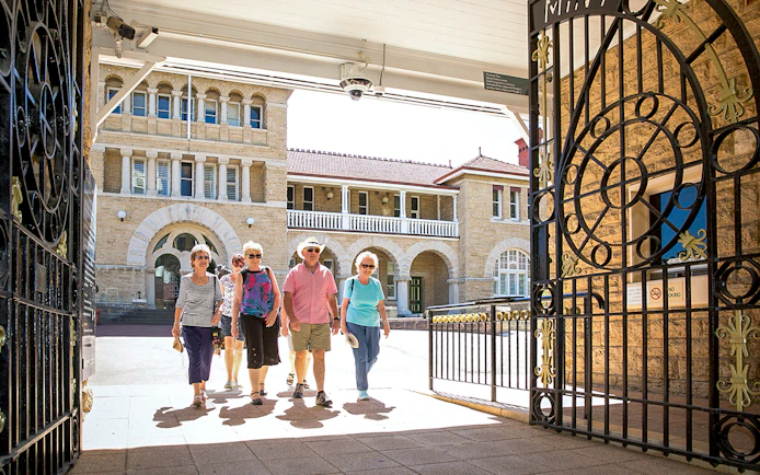 Visitors walking through ornate gates at a historic building in Perth's Kings Park.