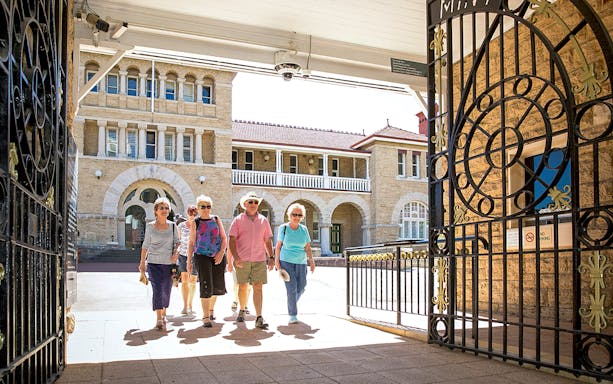 Visitors walking through ornate gates at a historic building in Perth's Kings Park.