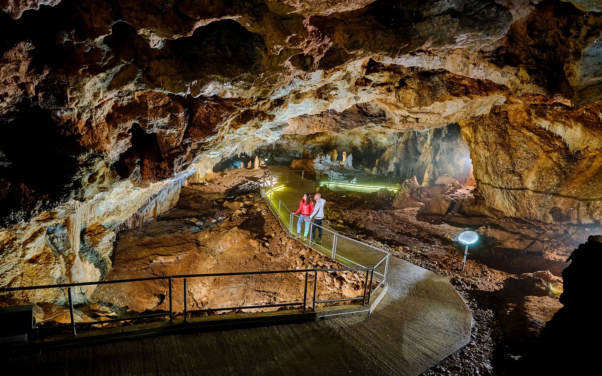 Tourists exploring illuminated path inside Lipa Cave, Cetinje.
