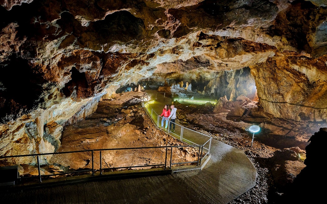 Tourists exploring illuminated path inside Lipa Cave, Cetinje.