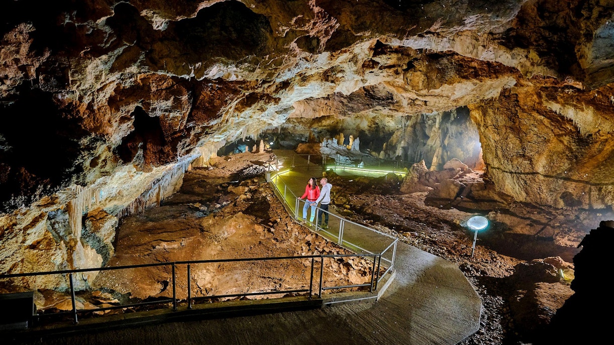 Tourists exploring illuminated path inside Lipa Cave, Cetinje.