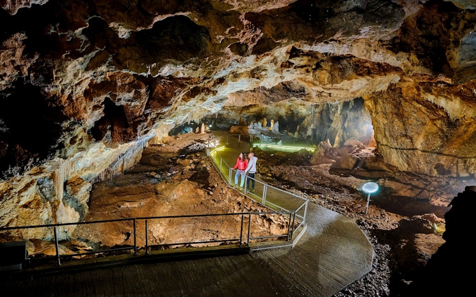 Tourists exploring illuminated path inside Lipa Cave, Cetinje.