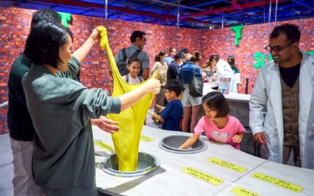 Children playing with yellow slime at Chaos Lab interactive exhibit.