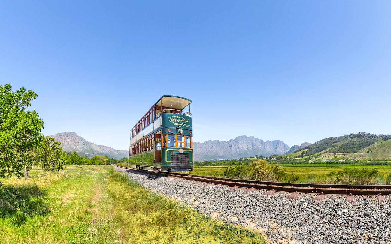 Tram on tracks through vineyards, Franschhoek Wine Tram Xplorer Tour, Cape Town.