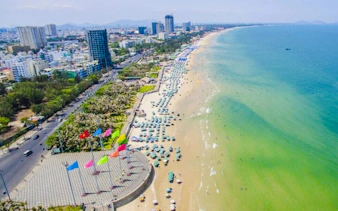 Aerial view of Vũng Tàu Beach with umbrellas and cityscape, part of a full-day tour from Ho Chi Minh City.