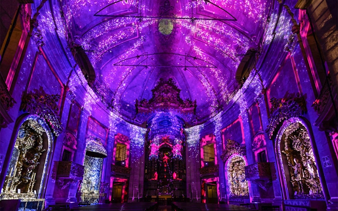 Clérigos Church interior with vibrant purple light display during Spiritus event.