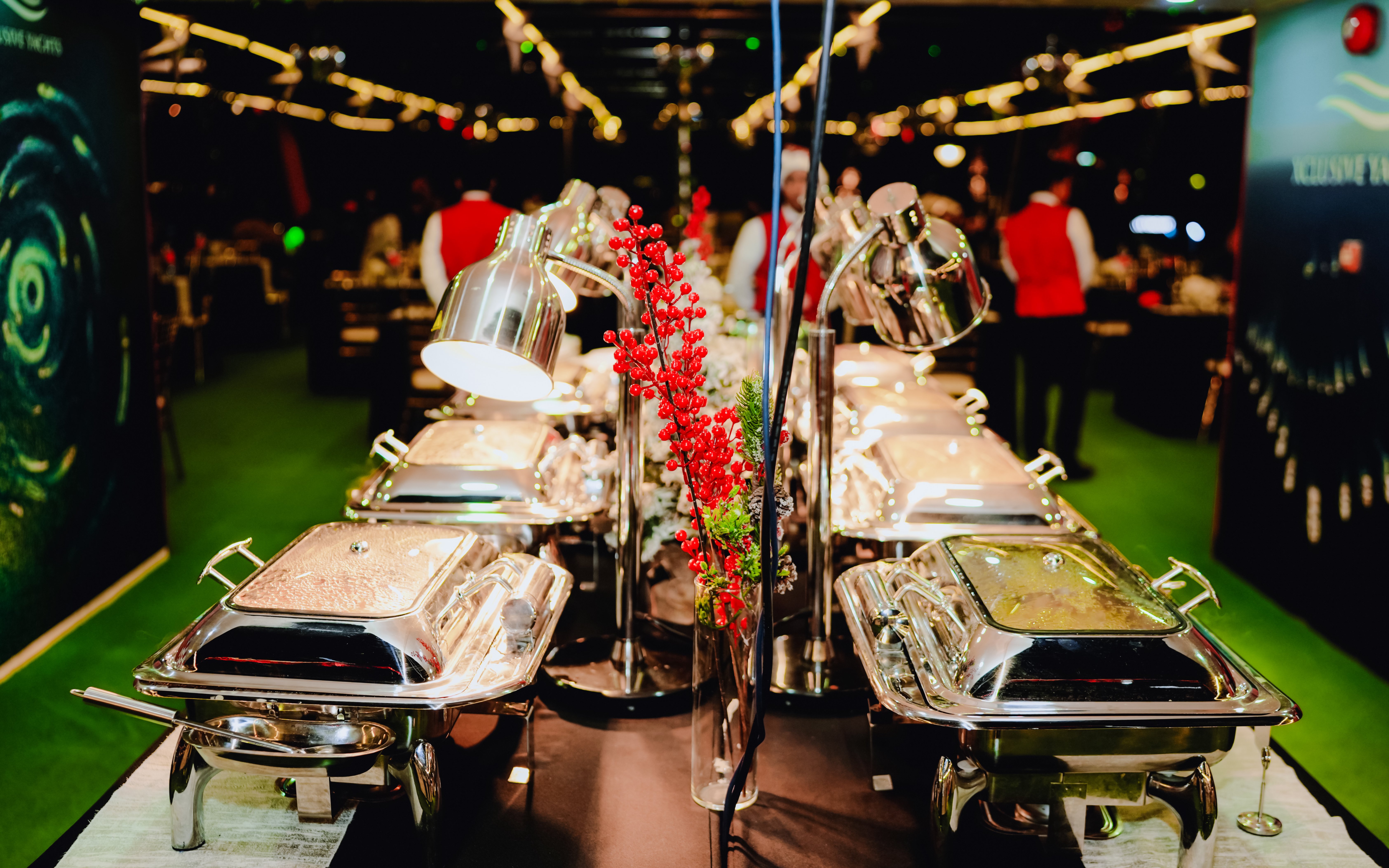 Buffet setup on a Christmas dinner cruise with festive decorations and chafing dishes.