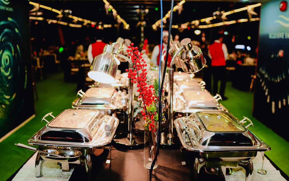 Buffet setup on a Christmas dinner cruise with festive decorations and chafing dishes.
