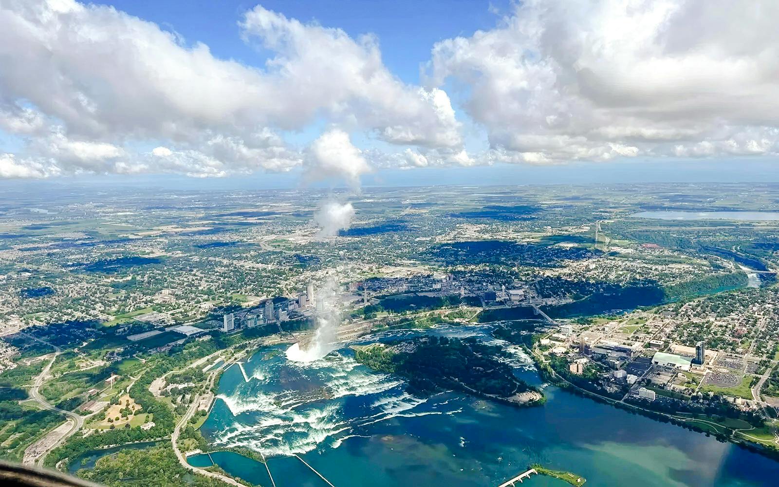 Aerial view of Niagara Falls with surrounding cityscape and river on the USA side.