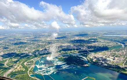 Aerial view of Niagara Falls with surrounding cityscape and river on the USA side.