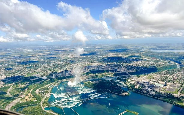 Aerial view of Niagara Falls with surrounding cityscape and river on the USA side.