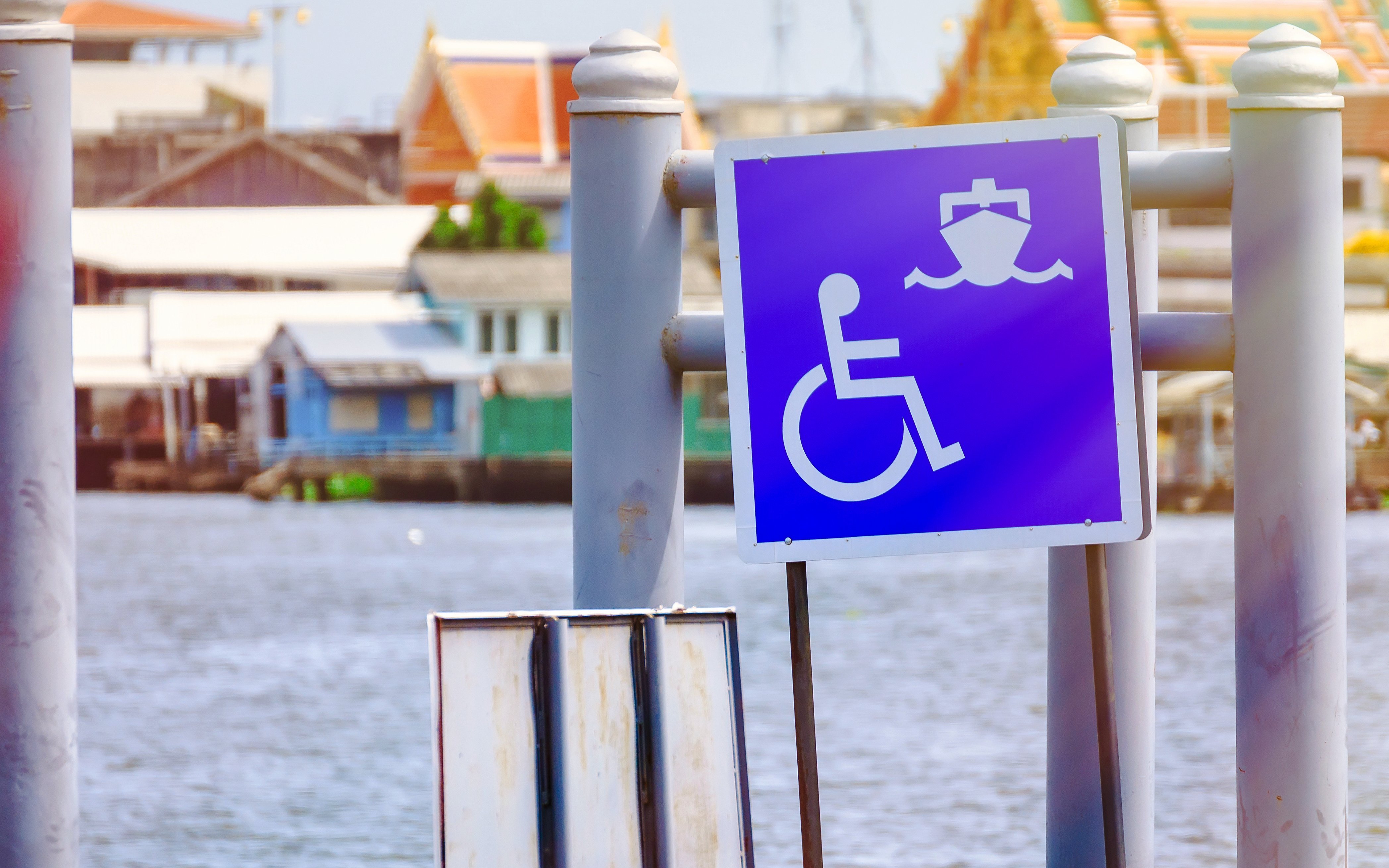 Wheelchair access sign at a pier with boats in the background.