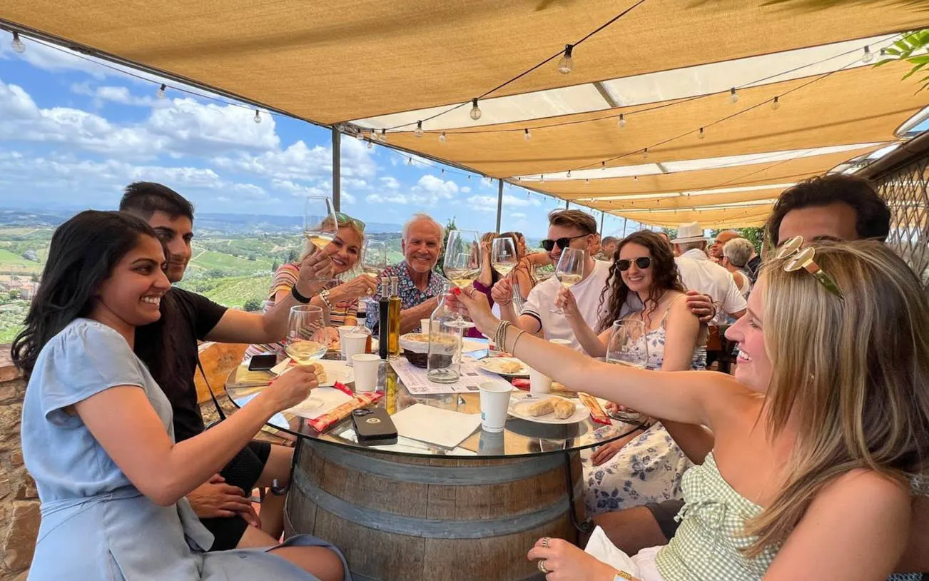 Group enjoying wine tasting at a Tuscan winery with scenic vineyard views.