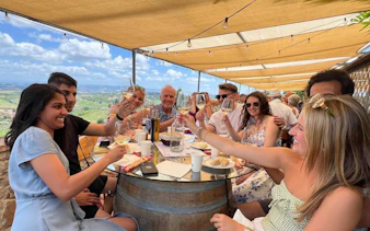 Group enjoying wine tasting at a Tuscan winery with scenic vineyard views.