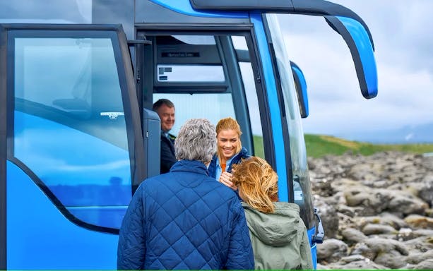 Visitors boarding a blue tour bus for Sky Lagoon in Reykjavik, Iceland.