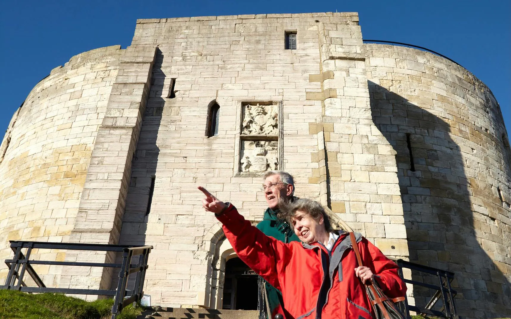Visitors exploring Clifford's Tower in York, pointing at historical features.