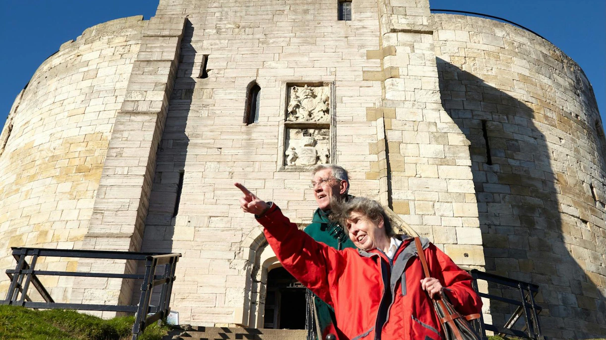 Visitors exploring Clifford's Tower in York, pointing at historical features.