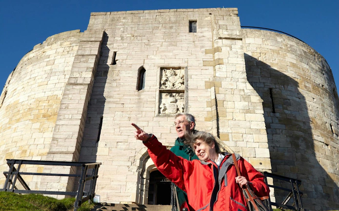 Visitors exploring Clifford's Tower in York, pointing at historical features.