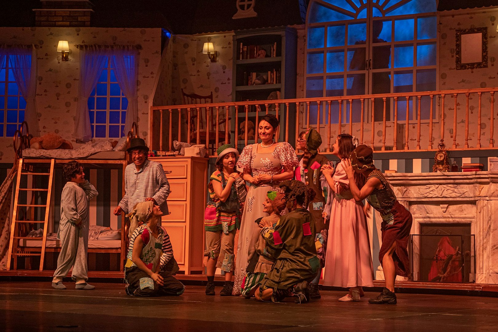 Cast performing a scene from "Peter, El musical" on stage with a bedroom set.