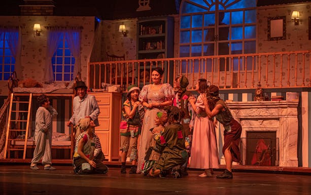 Cast performing a scene from "Peter, El musical" on stage with a bedroom set.