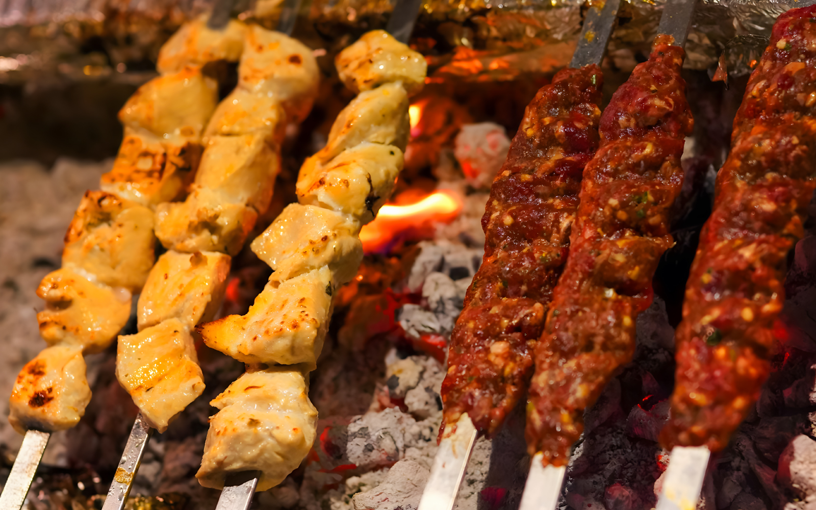 Barbecue skewers with chicken and meat grilling over coals at Royal dinner, Dubai.