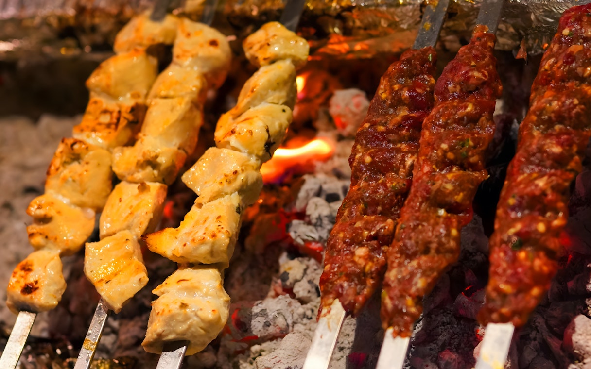 Barbecue skewers with chicken and meat grilling over coals at Royal dinner, Dubai.