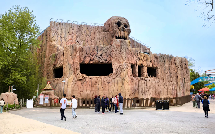 Skull Mountain ride exterior at Six Flags Great Adventure with visitors nearby.
