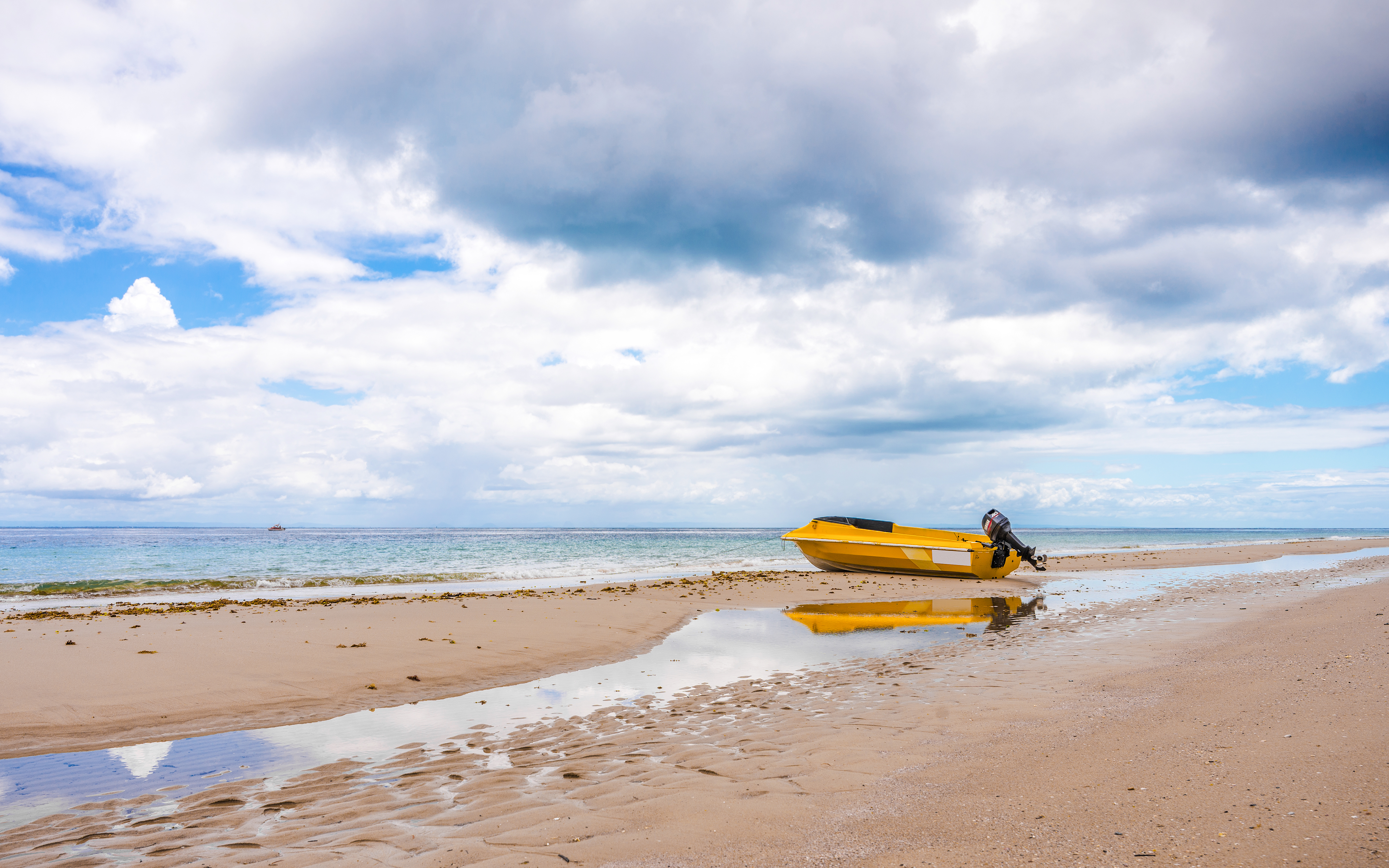 Yellow boat on sandy beach at low tide, Moreton Island, Queensland.