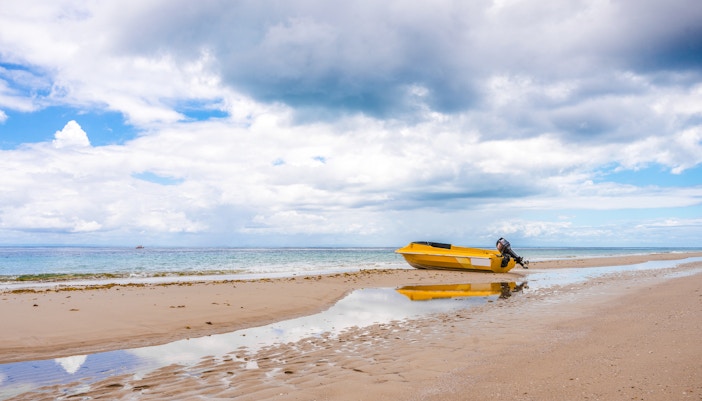 Yellow boat on sandy beach at low tide, Moreton Island, Queensland.