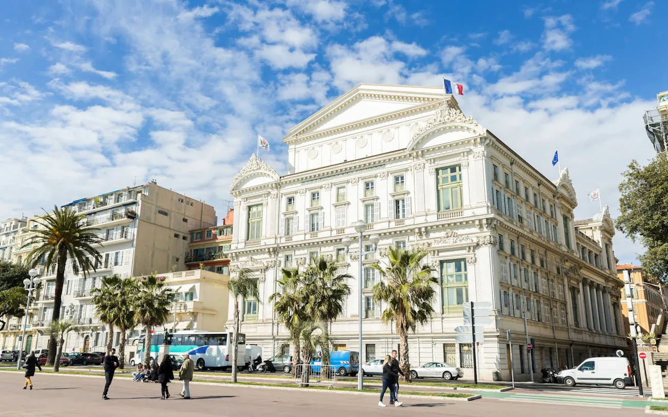 Nice city street with historic building and palm trees, part of Ghosts of the Riviera tour.