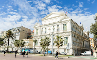 Nice city street with historic building and palm trees, part of Ghosts of the Riviera tour.